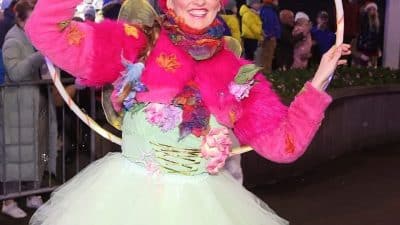 Performer Rachael is in a colourful pink and green fairy costume and holding a hula hoop