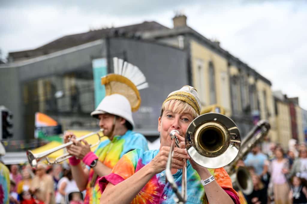 Performers playing music outdoor surrounded by audience