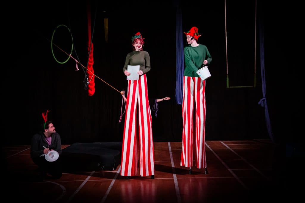 Two young people on stilts dressed in festive Christmas outfits