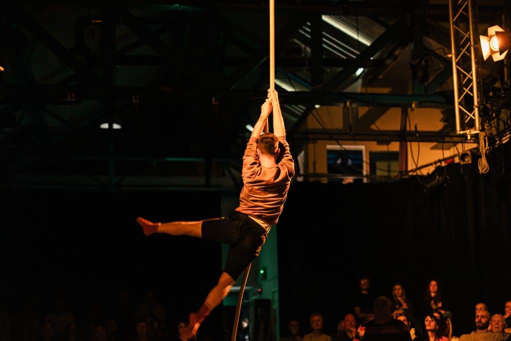 Person suspended in air holding on to a single rope