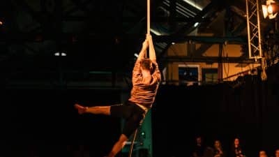 Person suspended in air holding on to a single rope